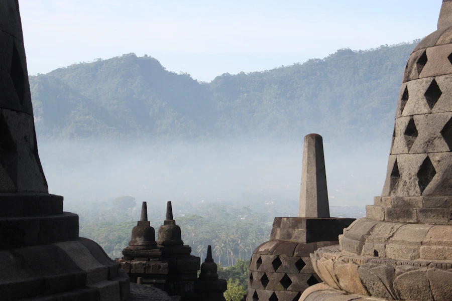 Stone stupas at Borobudur overlooking mist-covered green hills